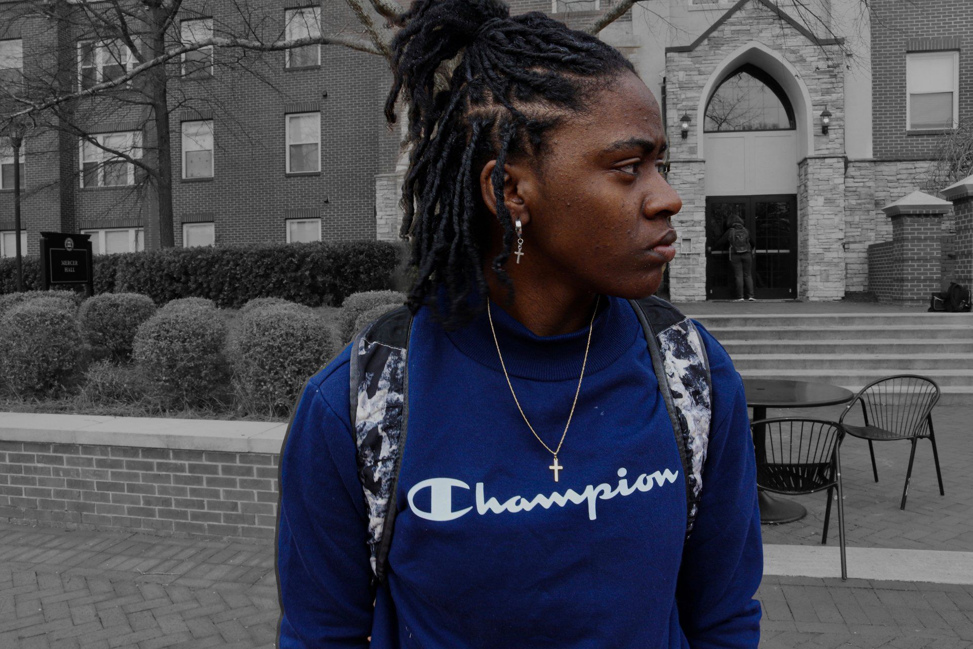 A man wearing a blue champion sweatshirt is standing in front of a building.