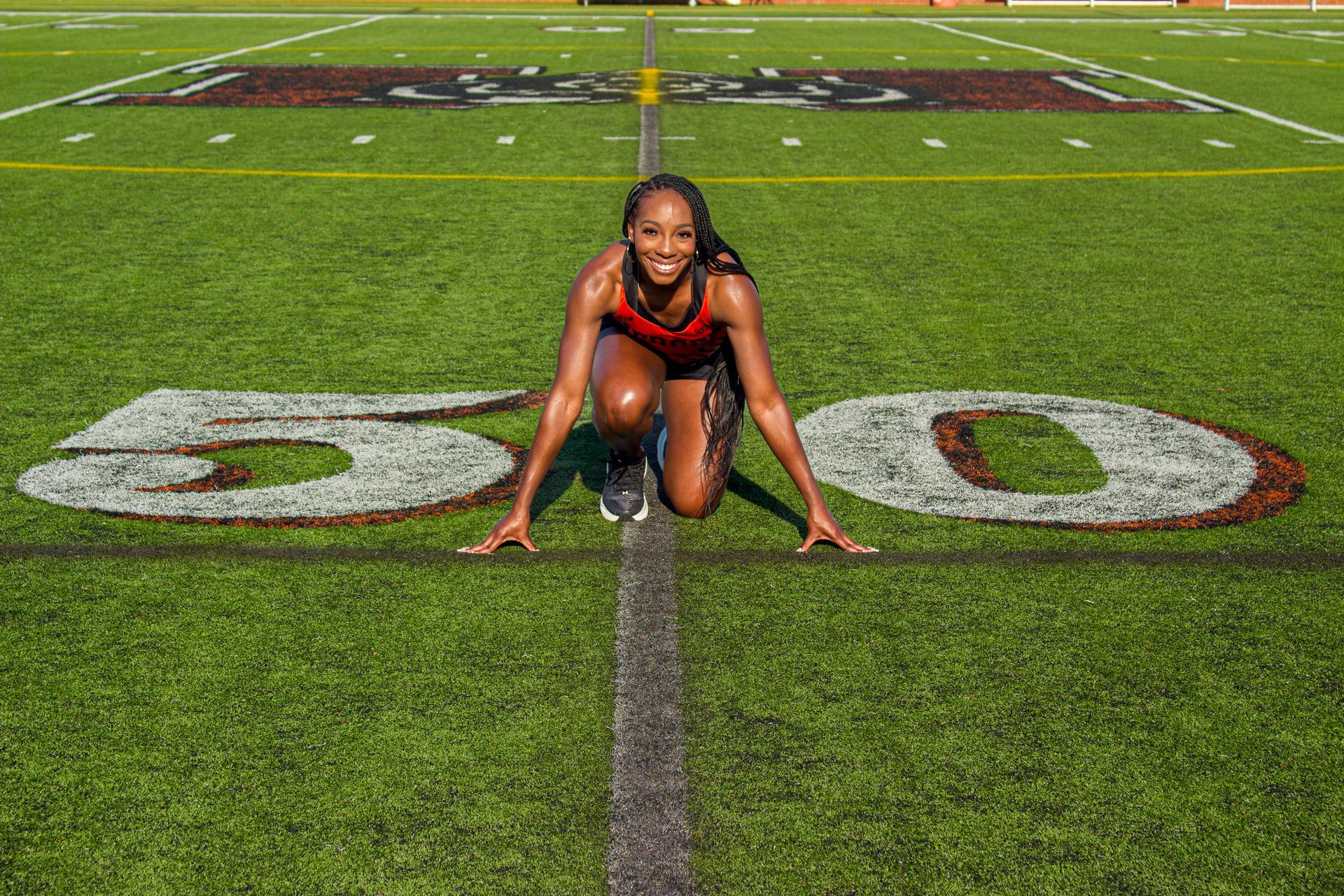 A woman is kneeling on a football field with the number 500 painted on the grass.