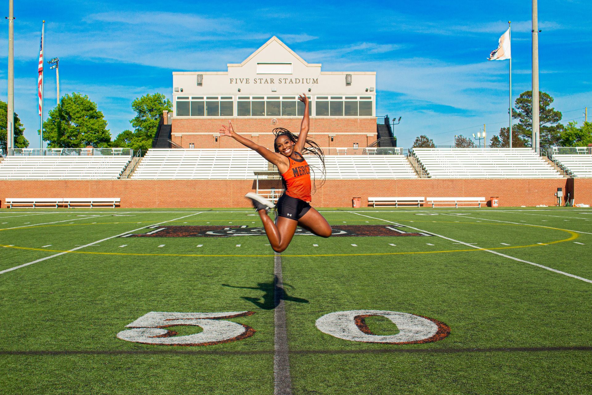A woman is jumping in the air on a football field.