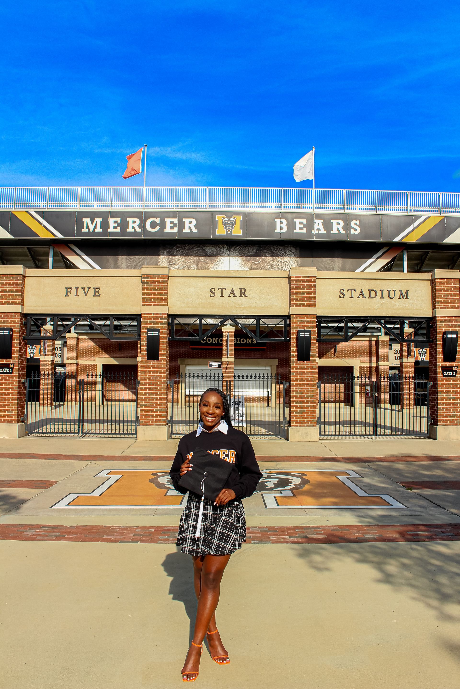 A woman is standing in front of the mercer bears stadium.