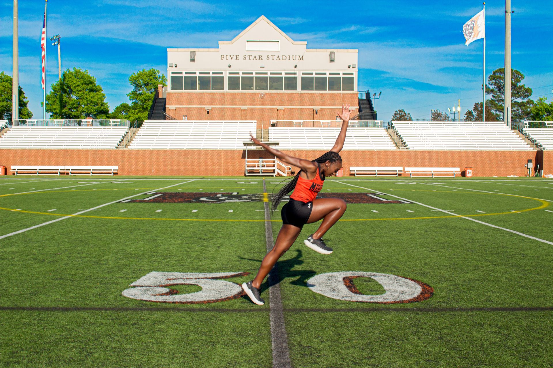 A woman is jumping in the air on a football field.