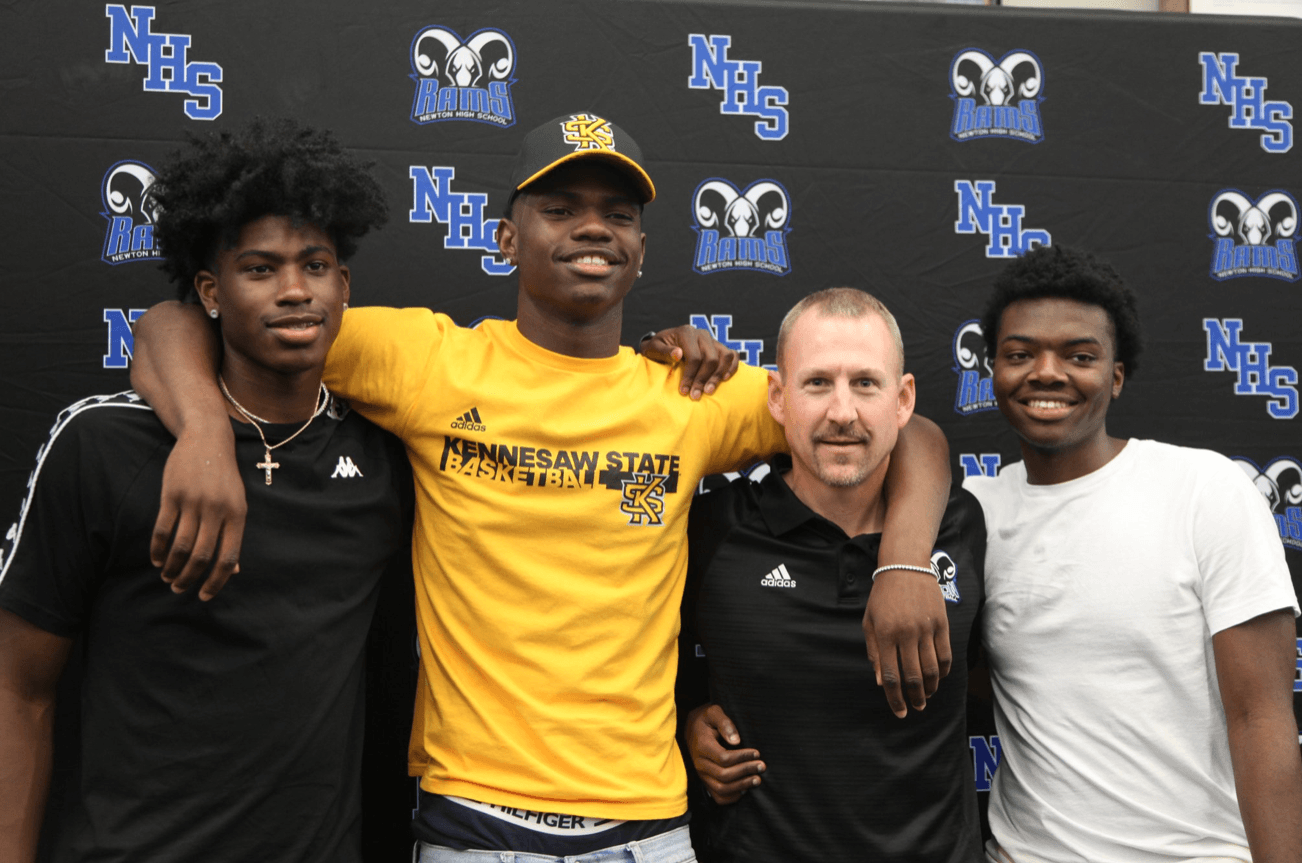 A group of young men are posing for a picture in front of a wall.