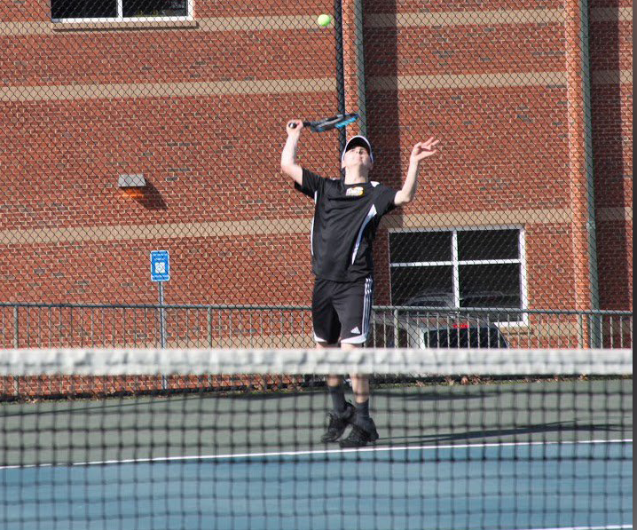 A man is serving a tennis ball on a tennis court.