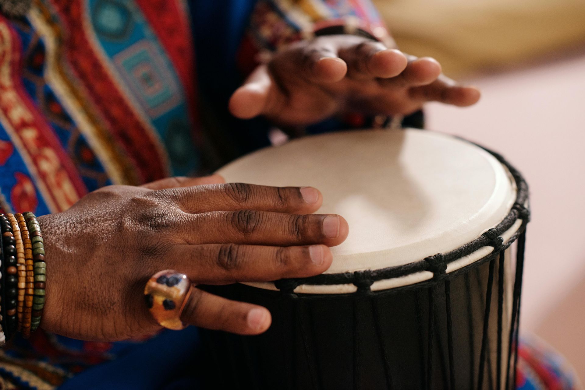 A close up of a person playing a drum with their hands.