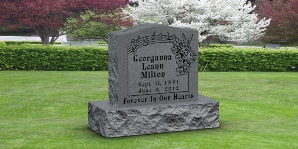 A gravestone in a cemetery with a tree in the background.