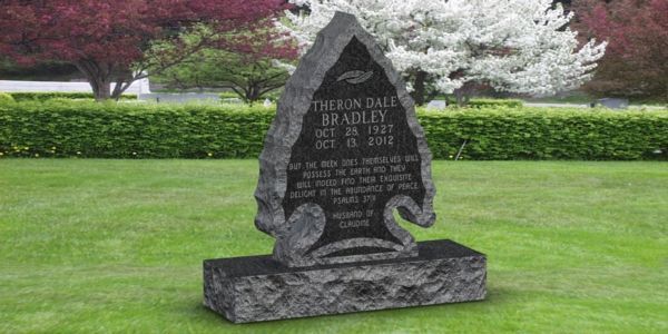 A gravestone in a cemetery with a tree in the background.