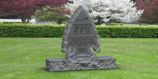 A gravestone in the shape of a tree in a cemetery.