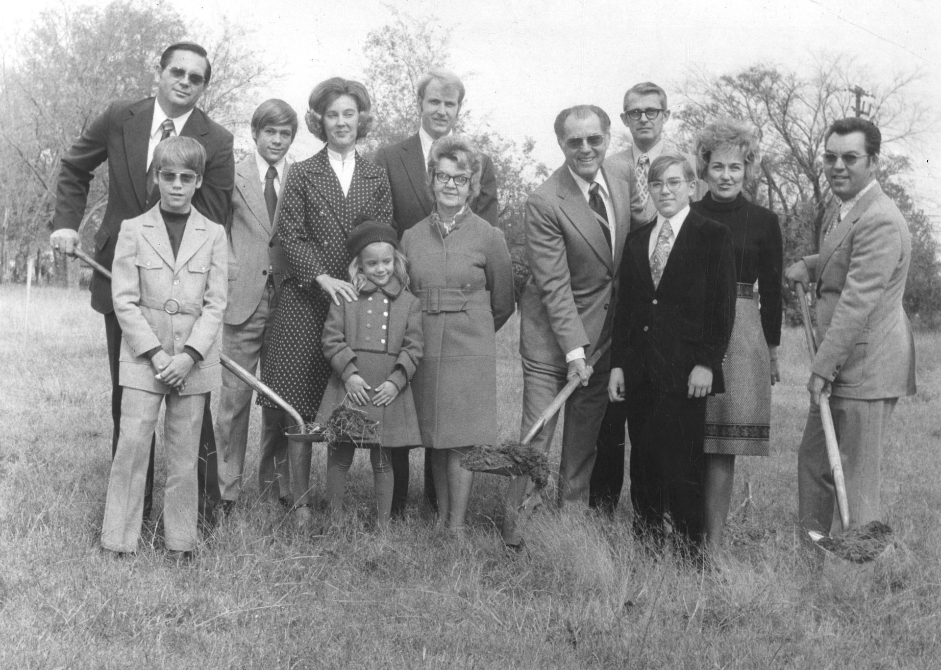 A group of people standing in a field holding shovels