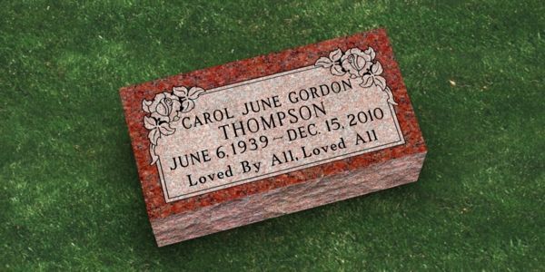 A gravestone for carol june gordon thompson is sitting on top of a lush green field.