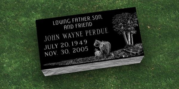 A gravestone for john wayne perdue is sitting on top of a lush green field.