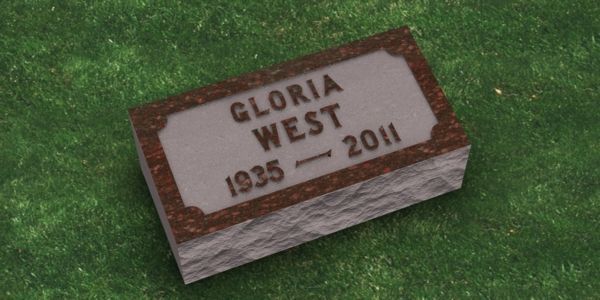 A gravestone for gloria west is sitting on top of a lush green field.