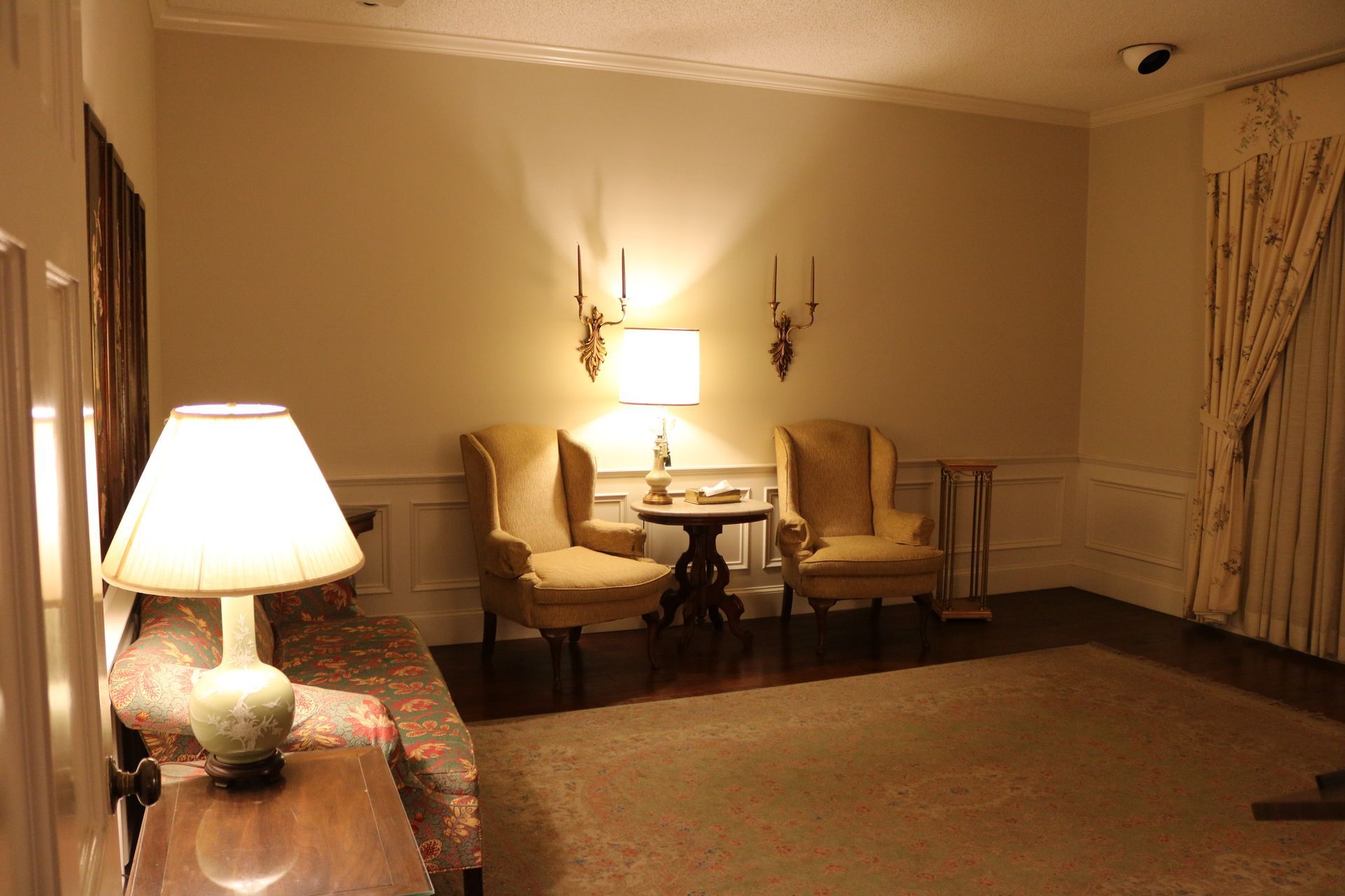 A living room with two chairs a table and a lamp