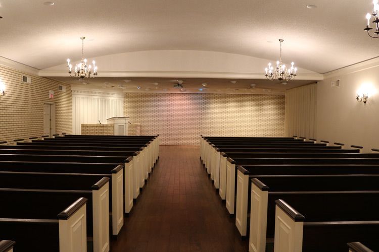 A church filled with rows of black benches and a podium.