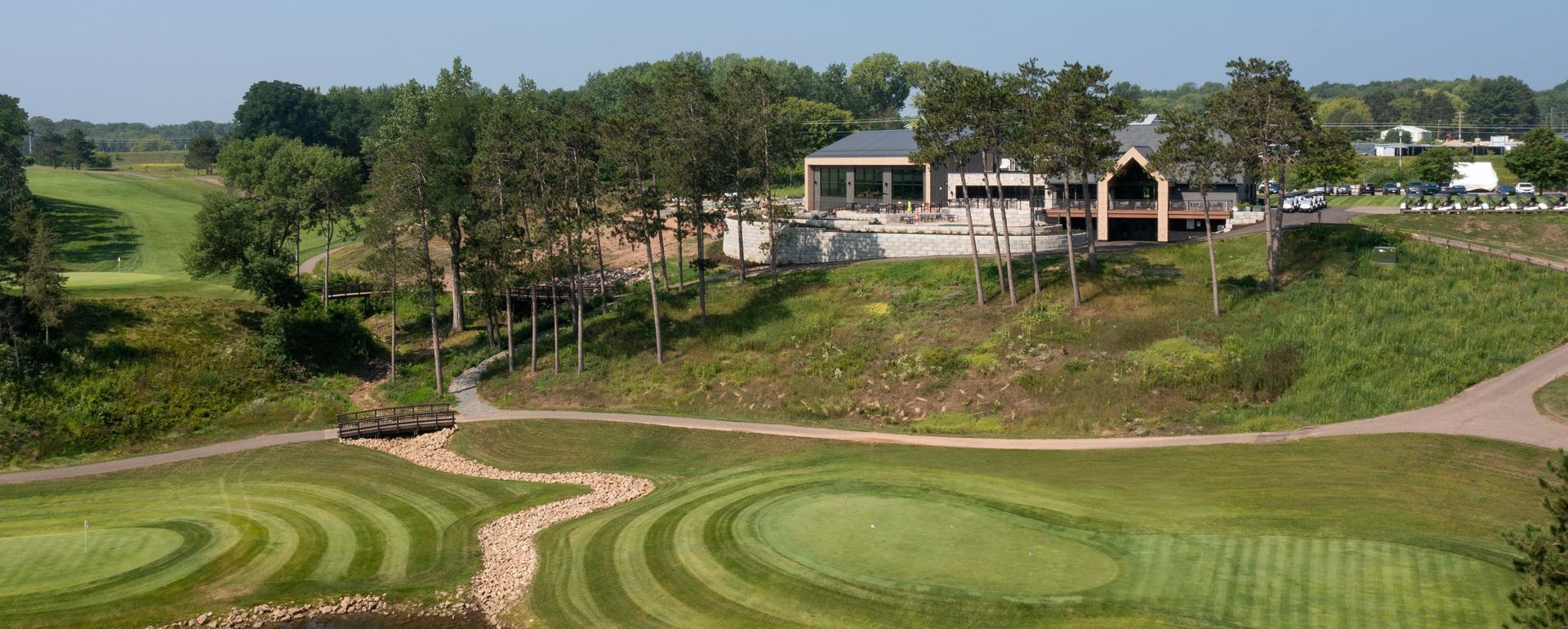 An aerial view of a golf course with a house in the background.