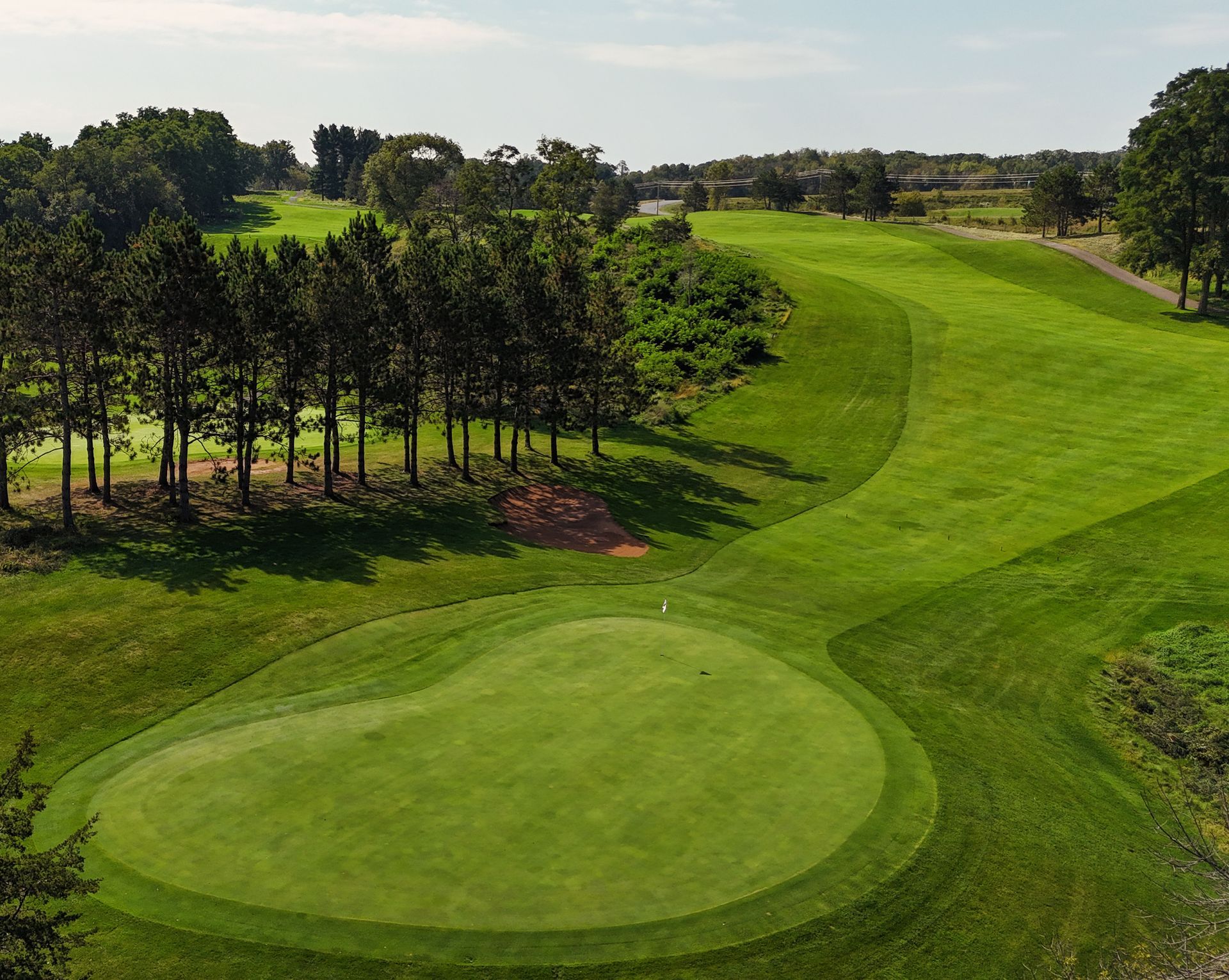 A golf course with trees and clouds in the sky