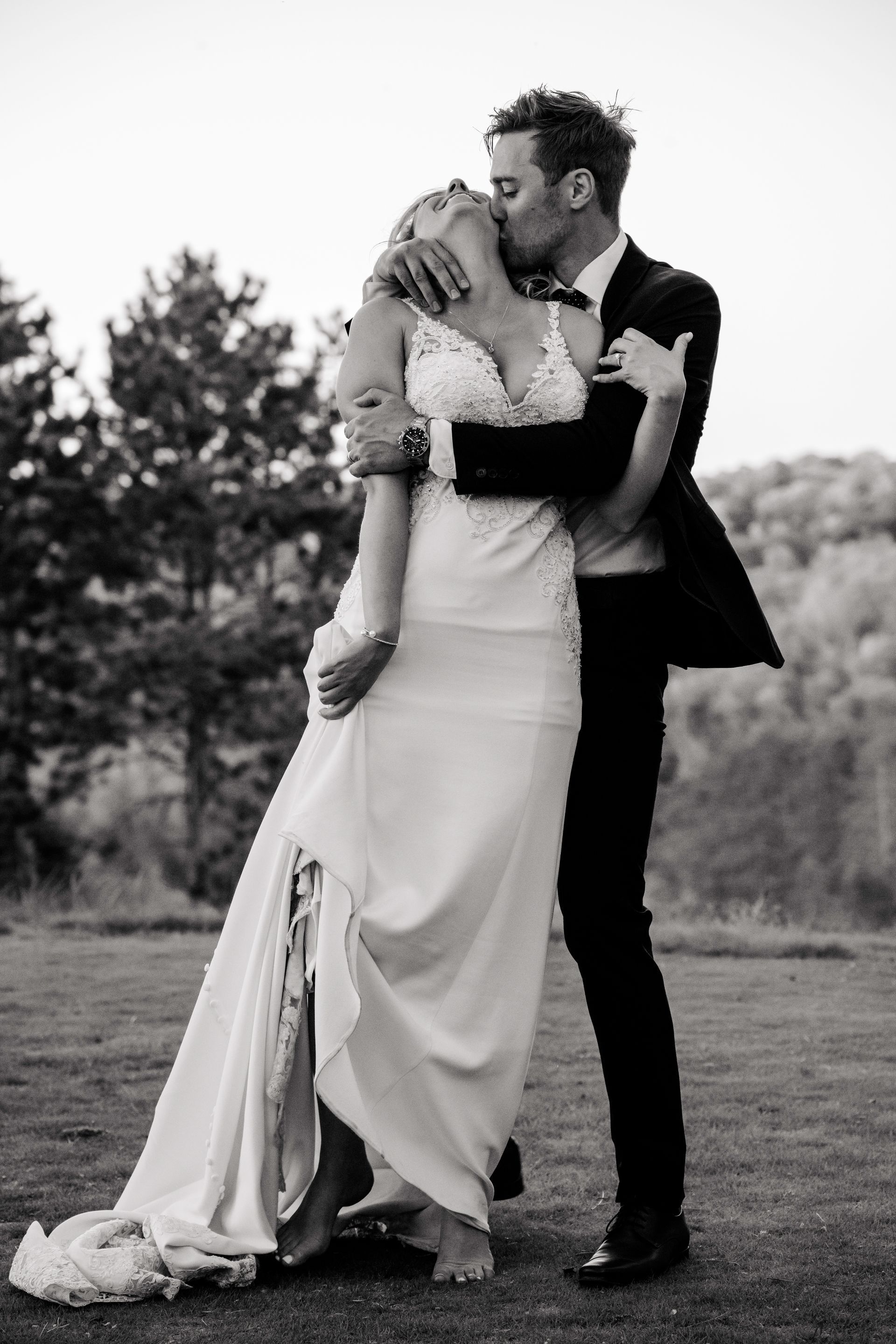 A bride and groom are standing on a wooden bridge.