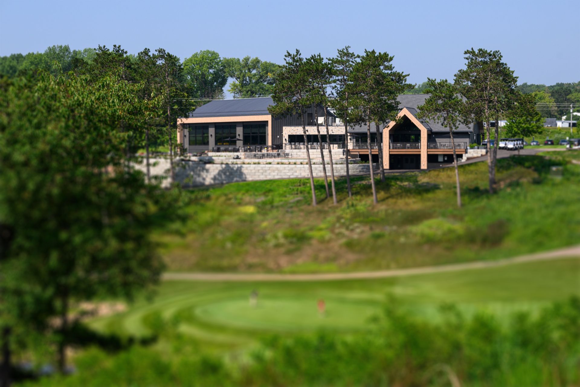 A golf course with a house in the background and a green in the foreground.