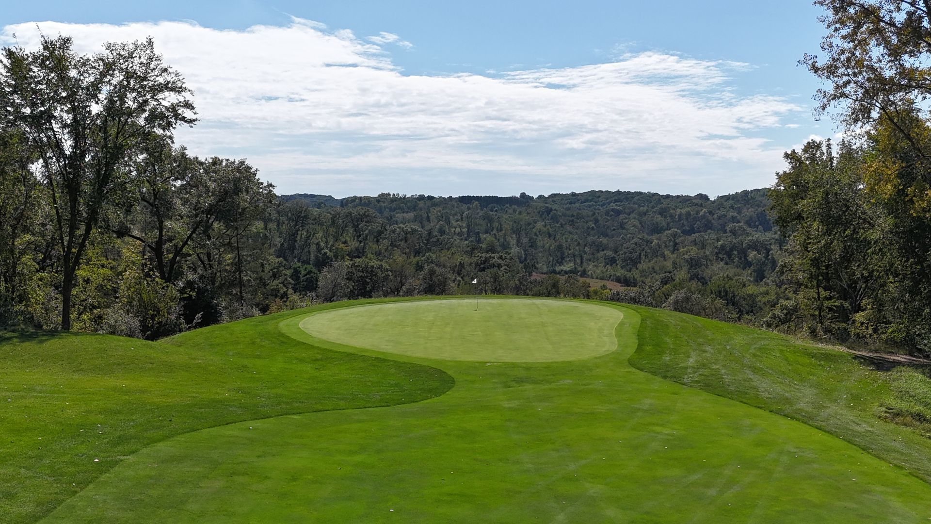 A golf course with trees and clouds in the sky