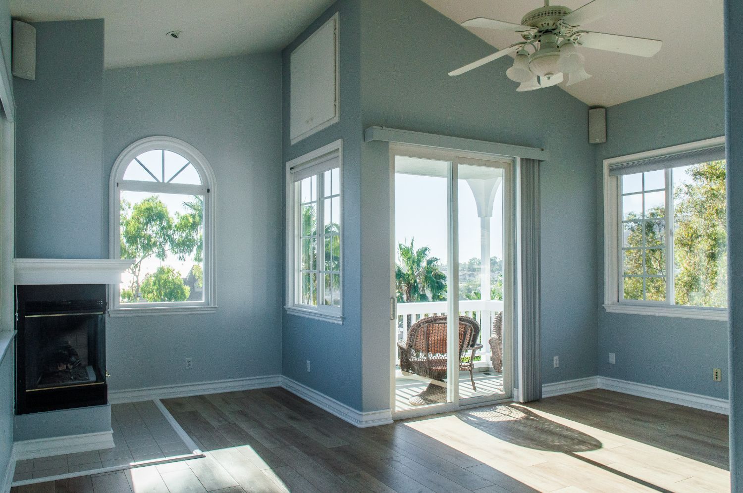 An empty living room with a fireplace and a ceiling fan.