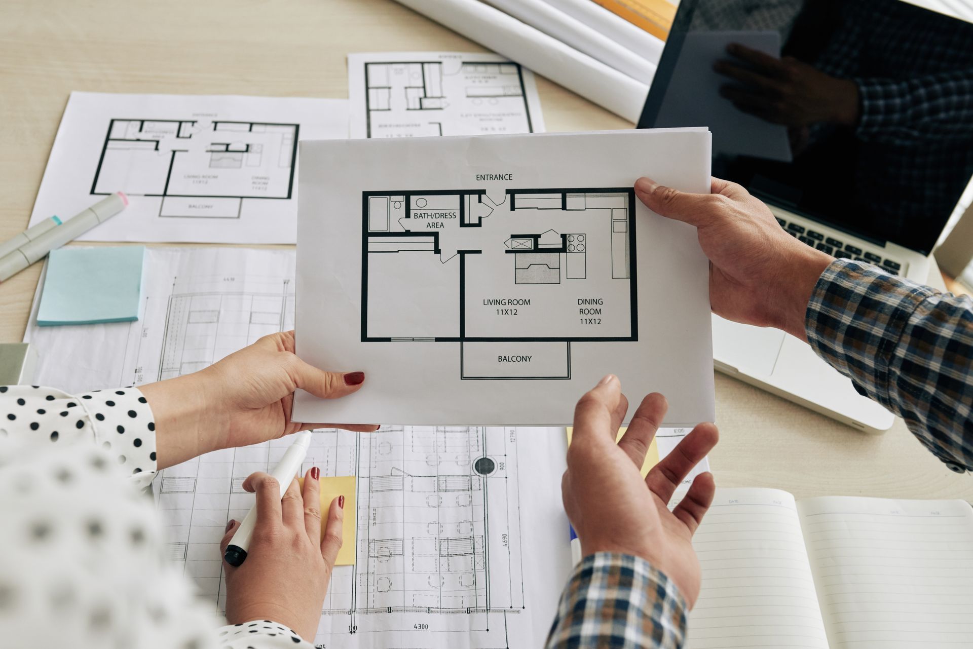 A man and a woman are looking at a floor plan of a house.