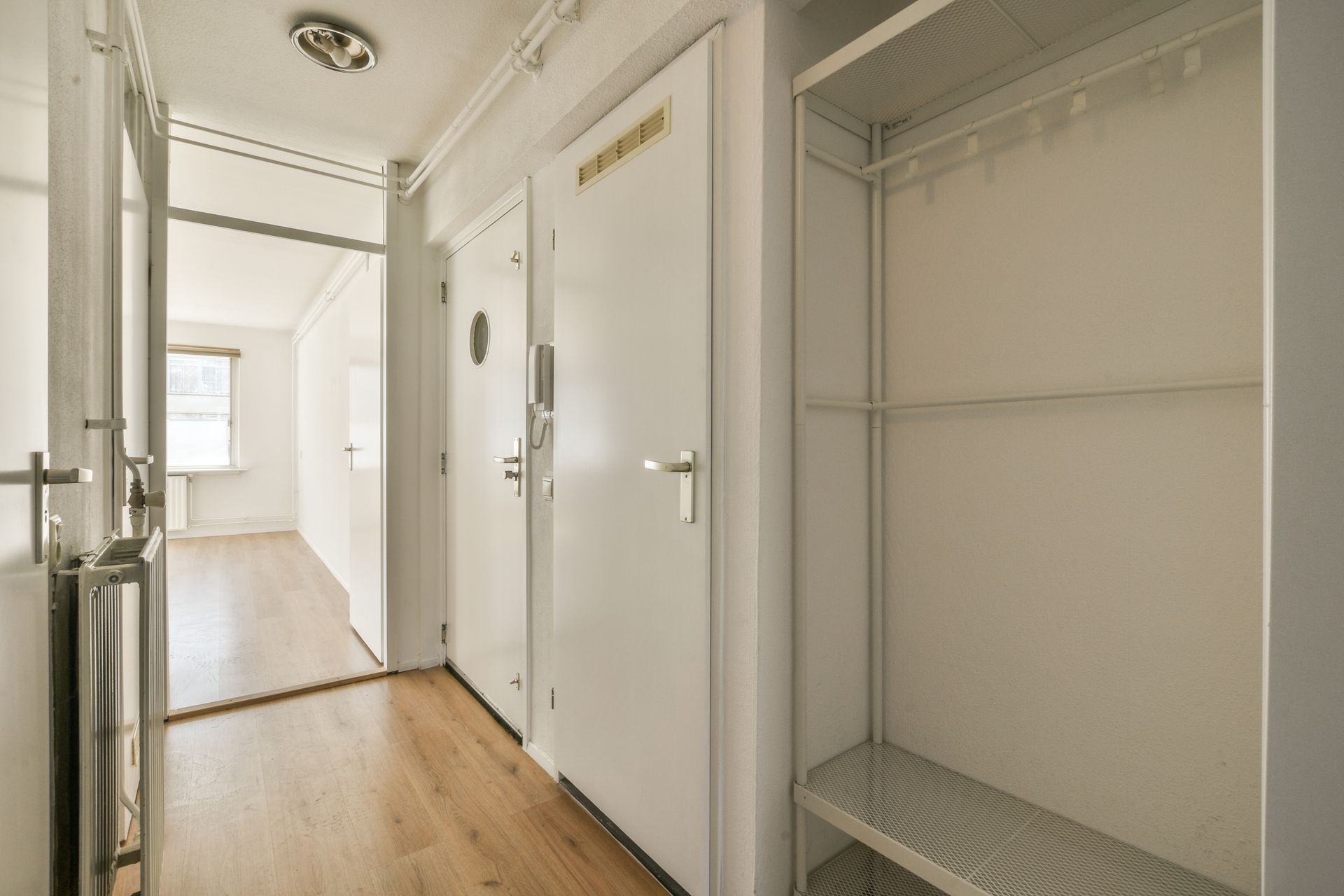 Bright, minimalist hallway with wooden floor and open closet.