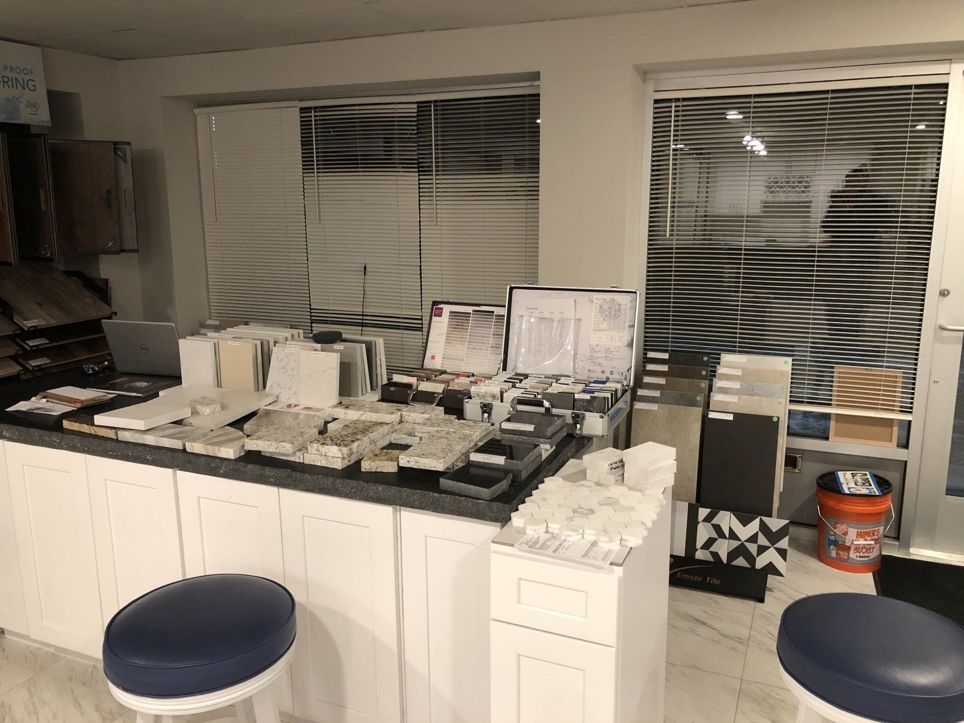 A tile showroom with a table and stools in it and a window.