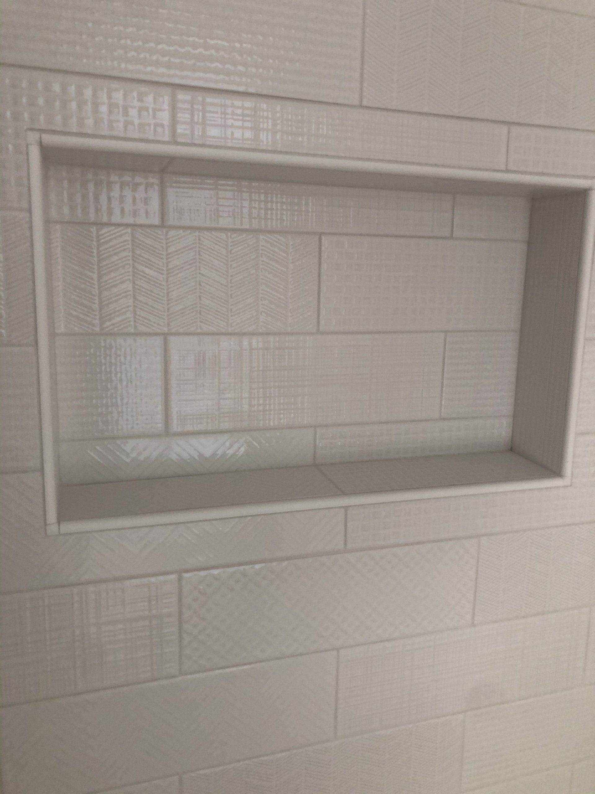 A shower niche idea in a bathroom with white tiles on the wall.
