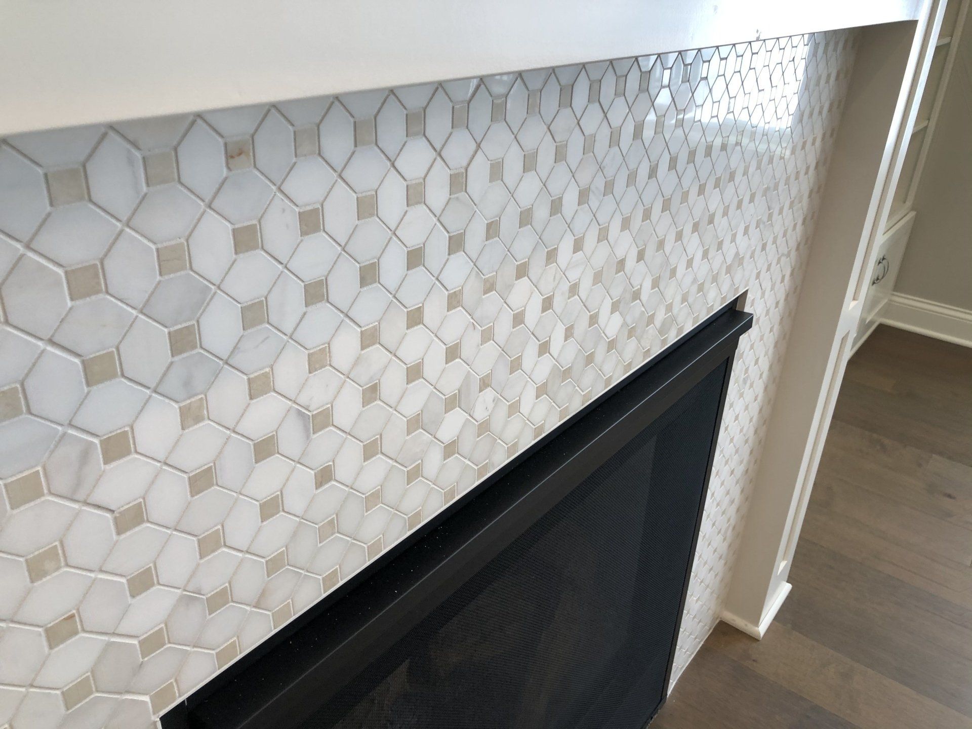 A fireplace with a white tile surround and a black screen.