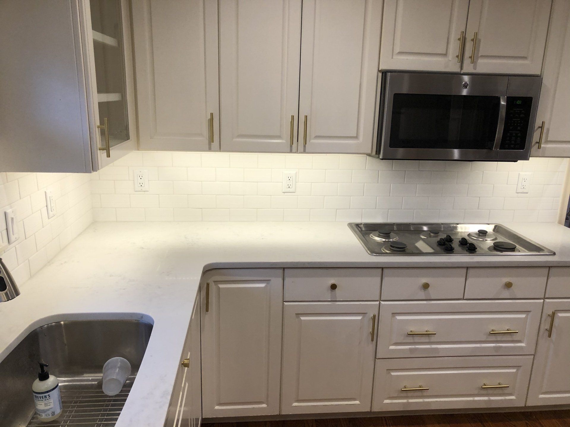 Backsplash installation | A kitchen with white cabinets and stainless steel appliances