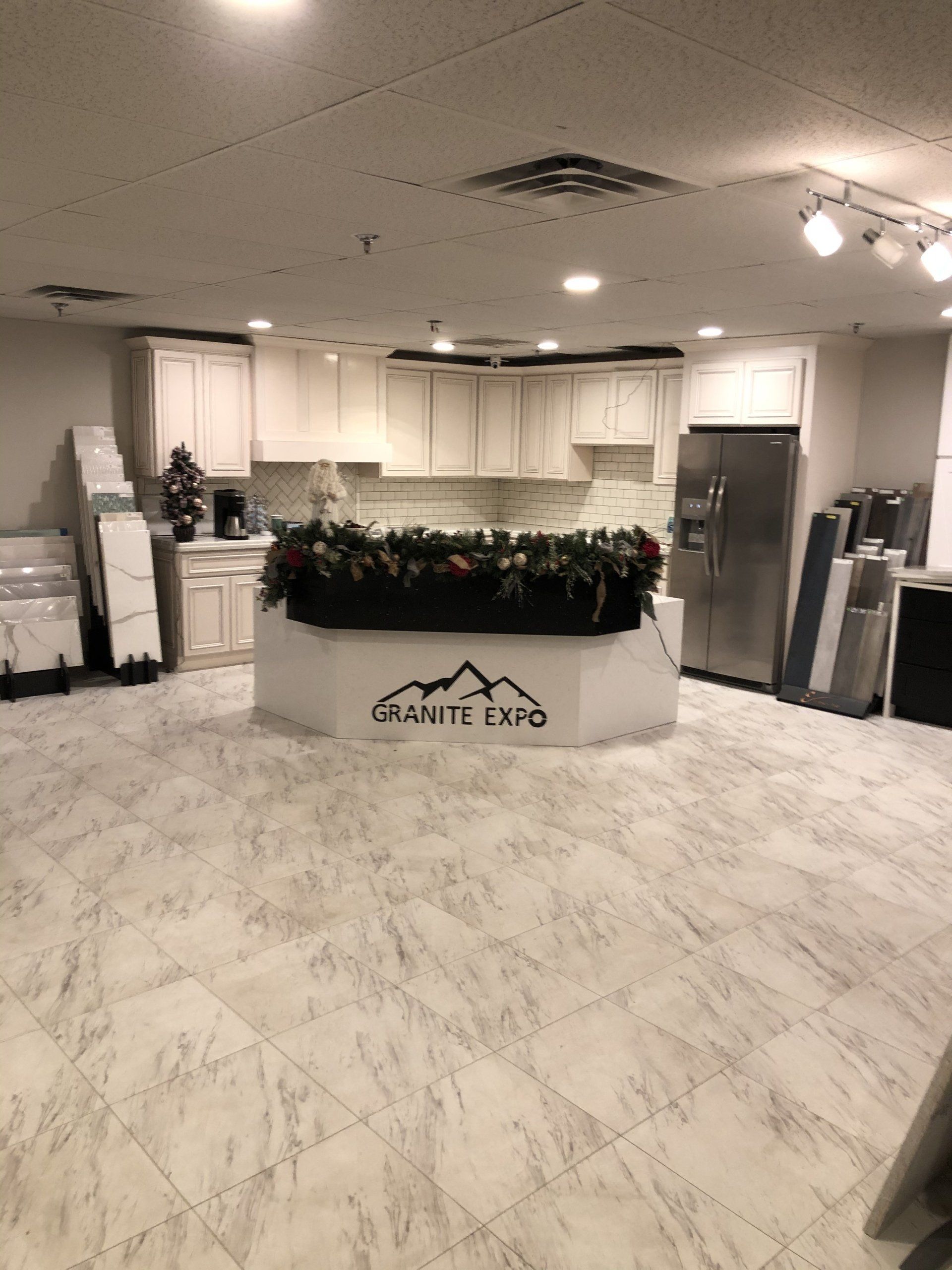 A kitchen with white cabinets , a stainless steel refrigerator , and a granite counter top.