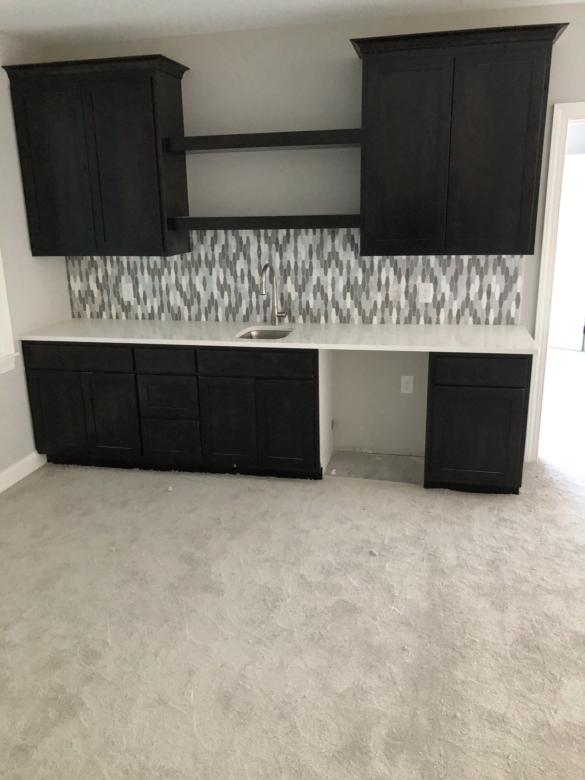 A kitchen with black cabinets and white counter tops