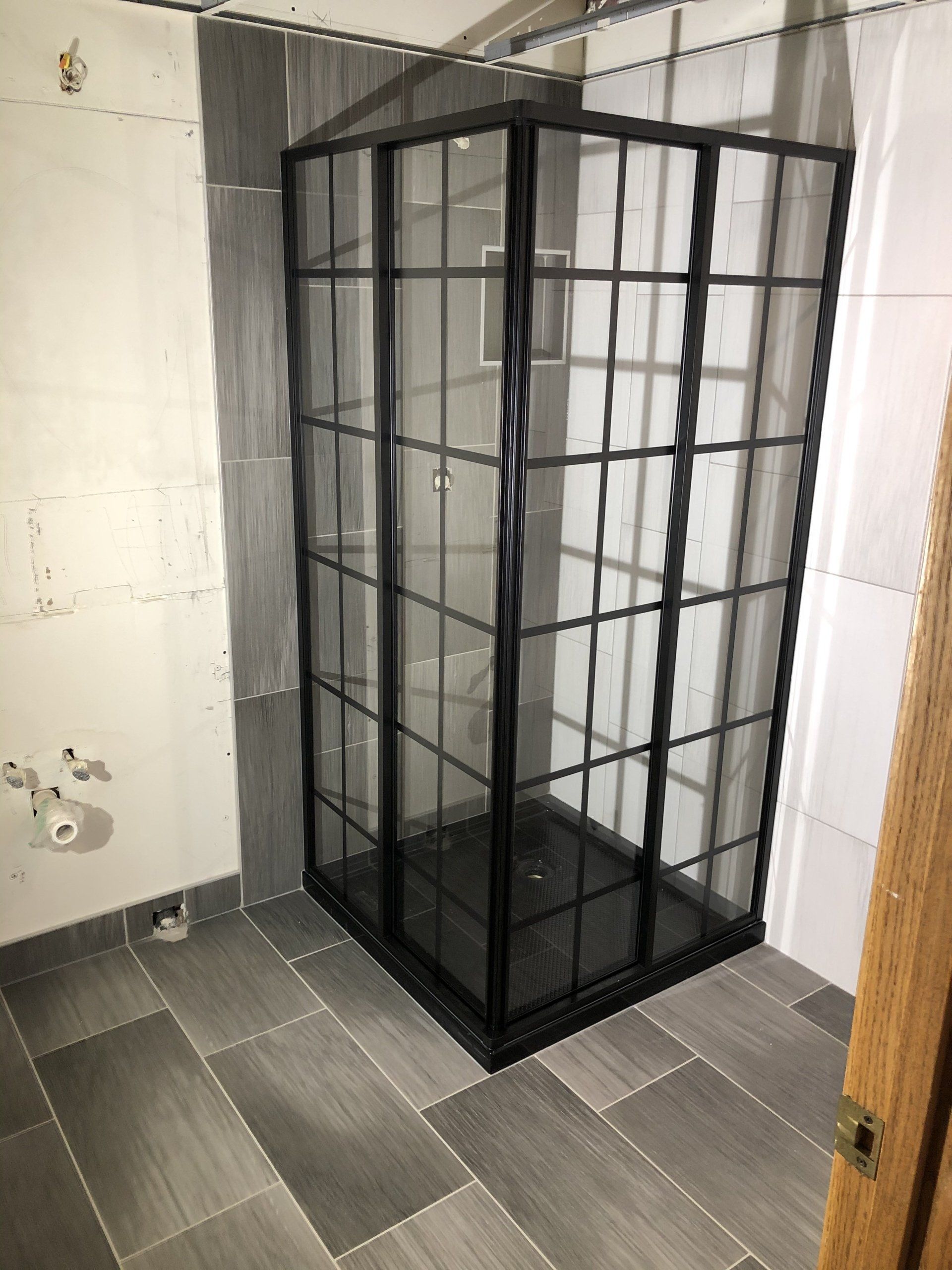 A bathroom with a black shower stall and a tiled floor.