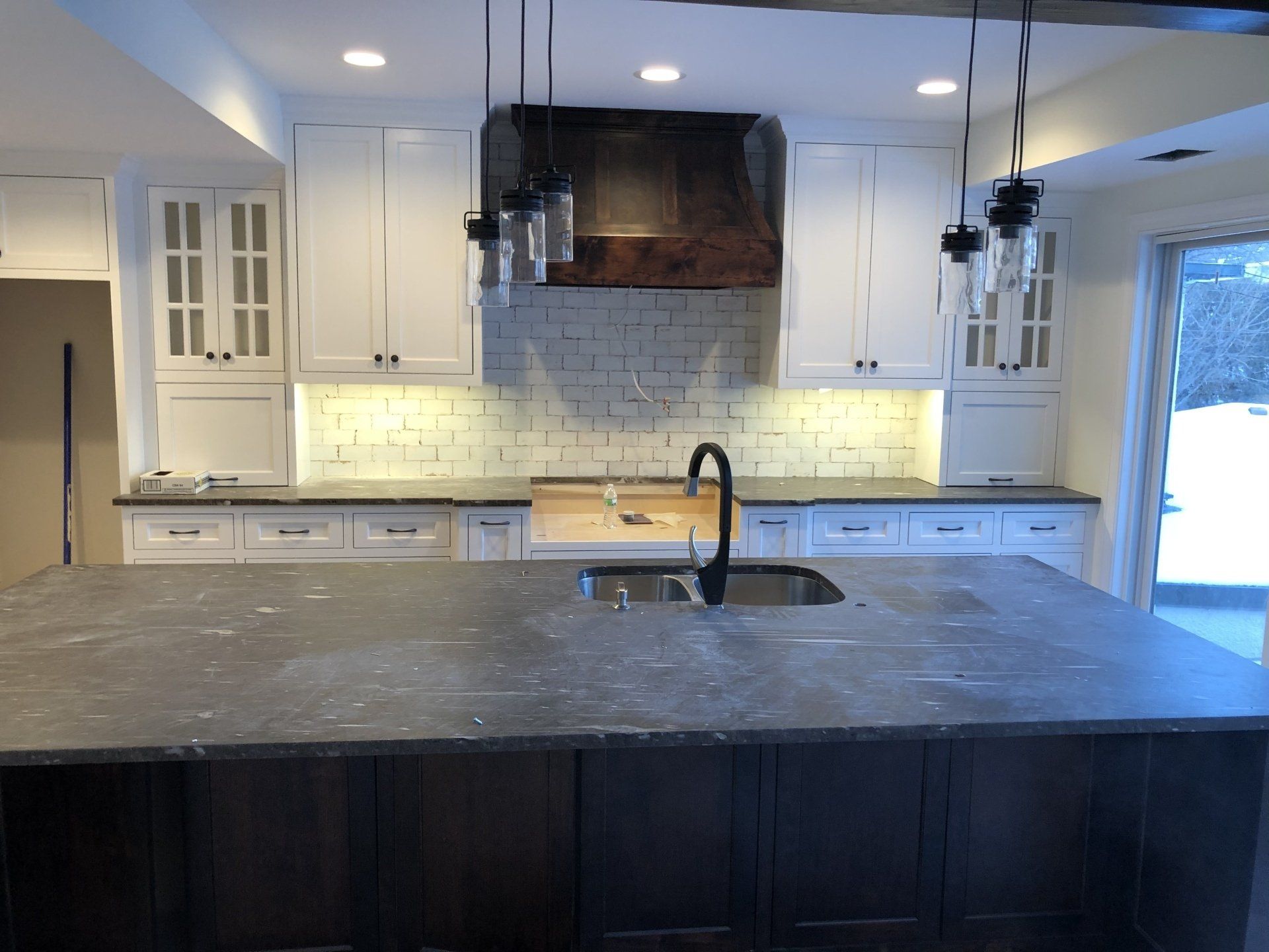 A renovated kitchen with a large island and a sink.