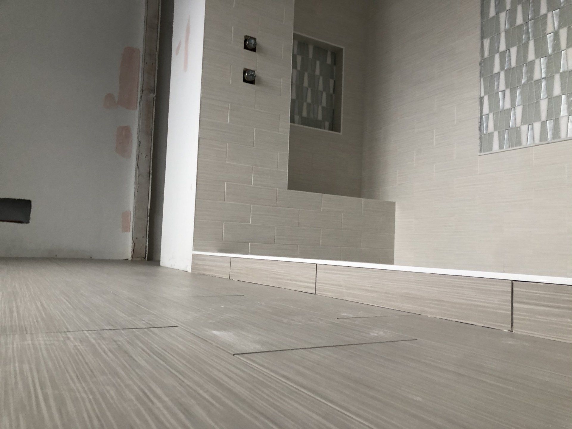 A renovated bathroom with a wooden floor and white tiles.