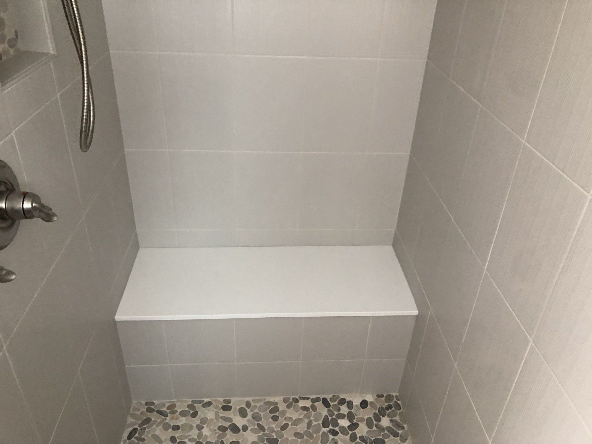 A shower reno with a bench and a shower head.