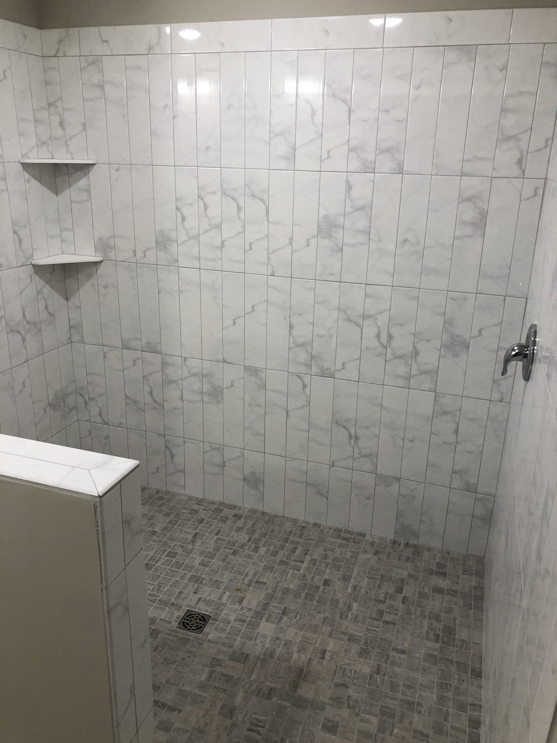 An accessible bathroom with white tiles and a walk in shower.