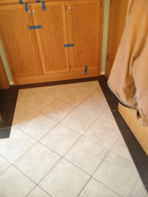 A tiled floor in a room with wooden cabinets