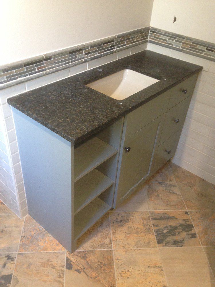 A bathroom vanity with a black counter top and a sink