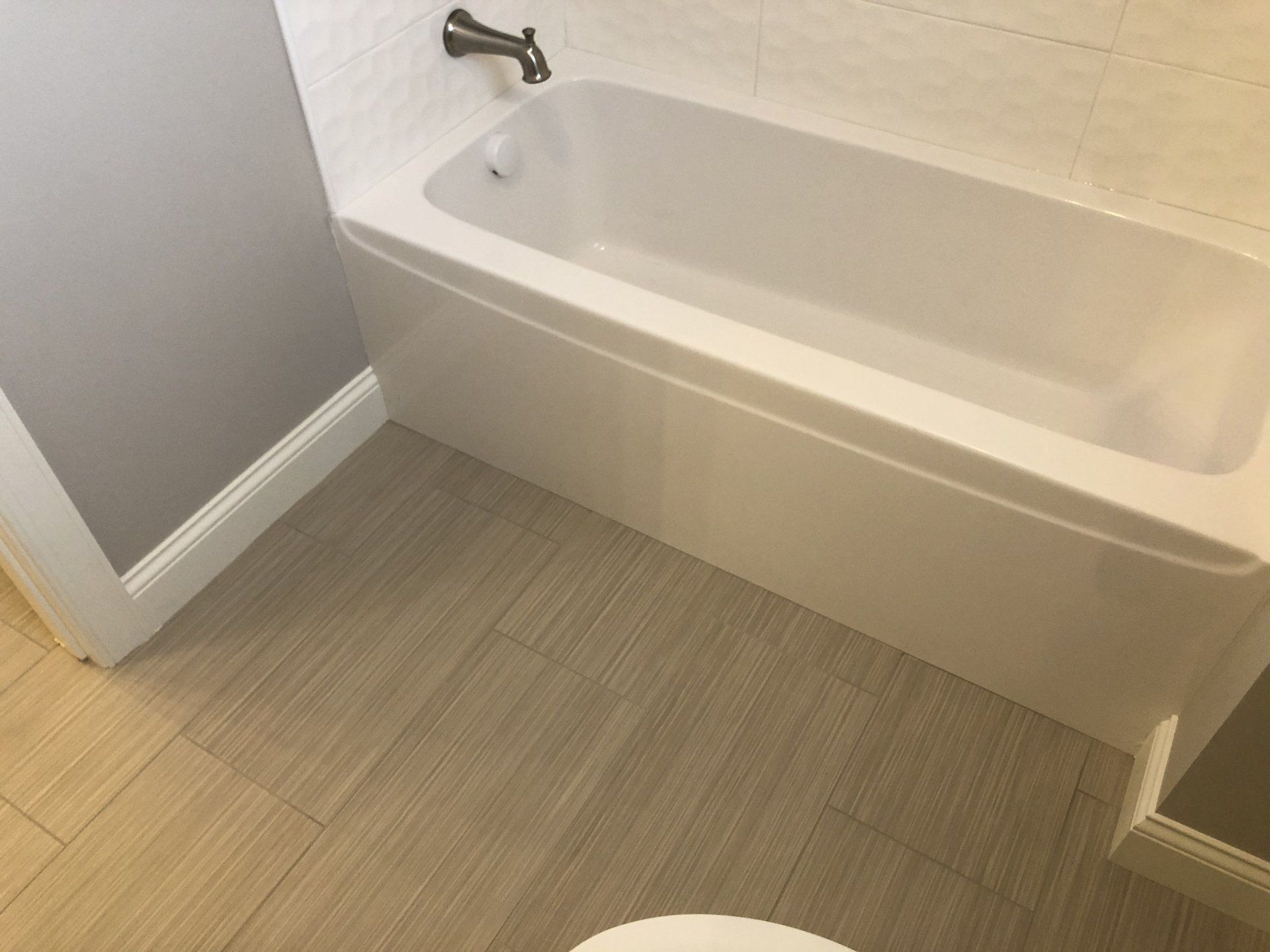 Bathroom shower conversions | A white bathtub is sitting next to a toilet in a bathroom.