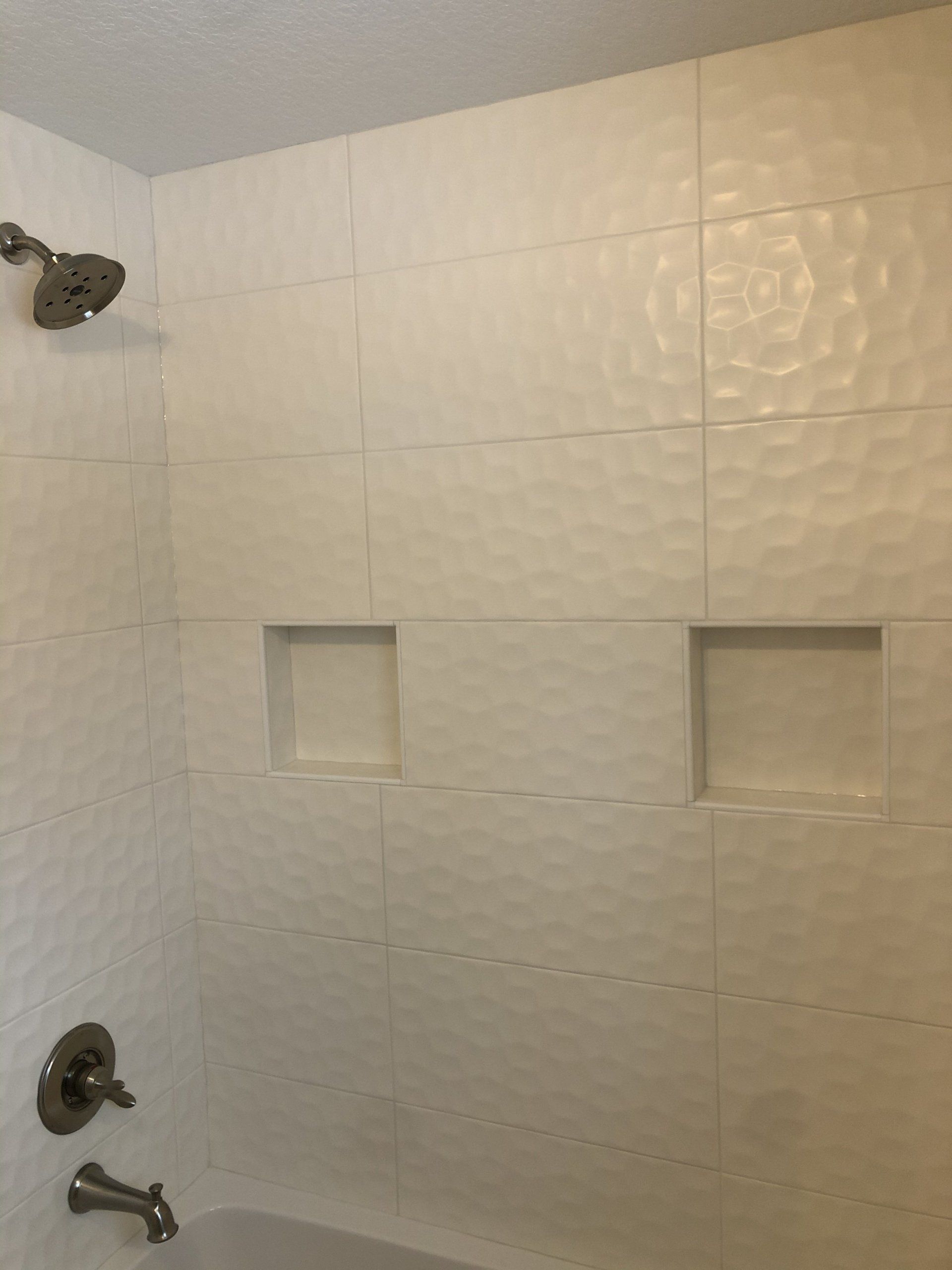 A bathroom with a tub , shower , and two niches.