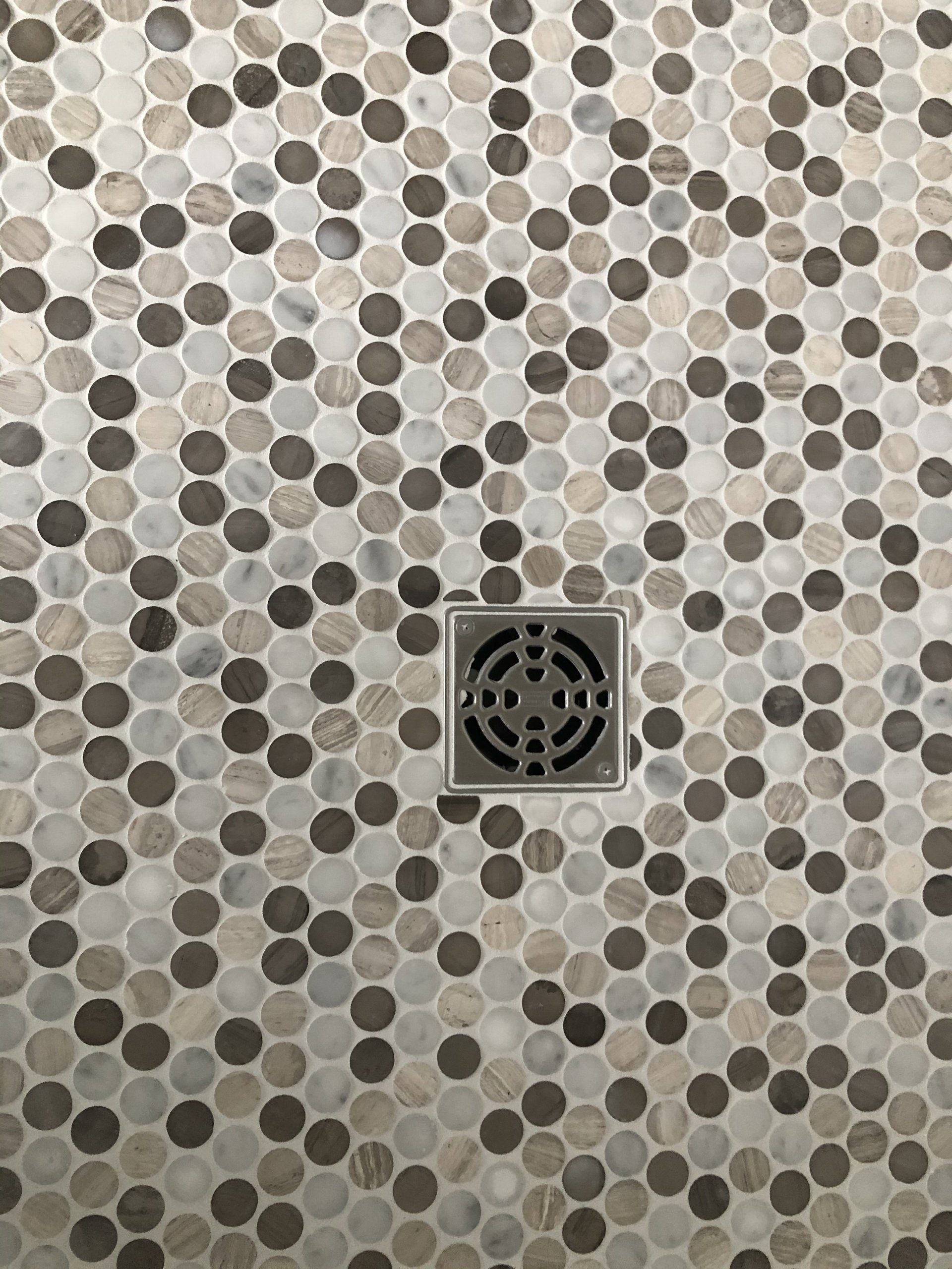 A close up of a shower floor with polka dots and a drain.