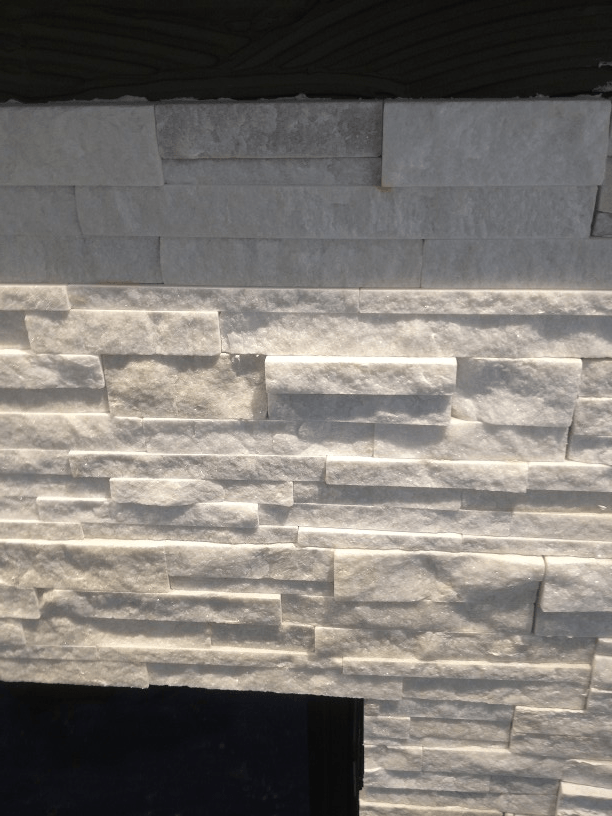 A fireplace with a white stone wall behind it