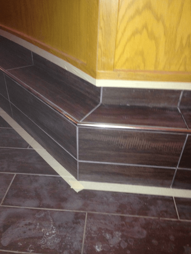 A brown tile floor with a yellow wall in the background