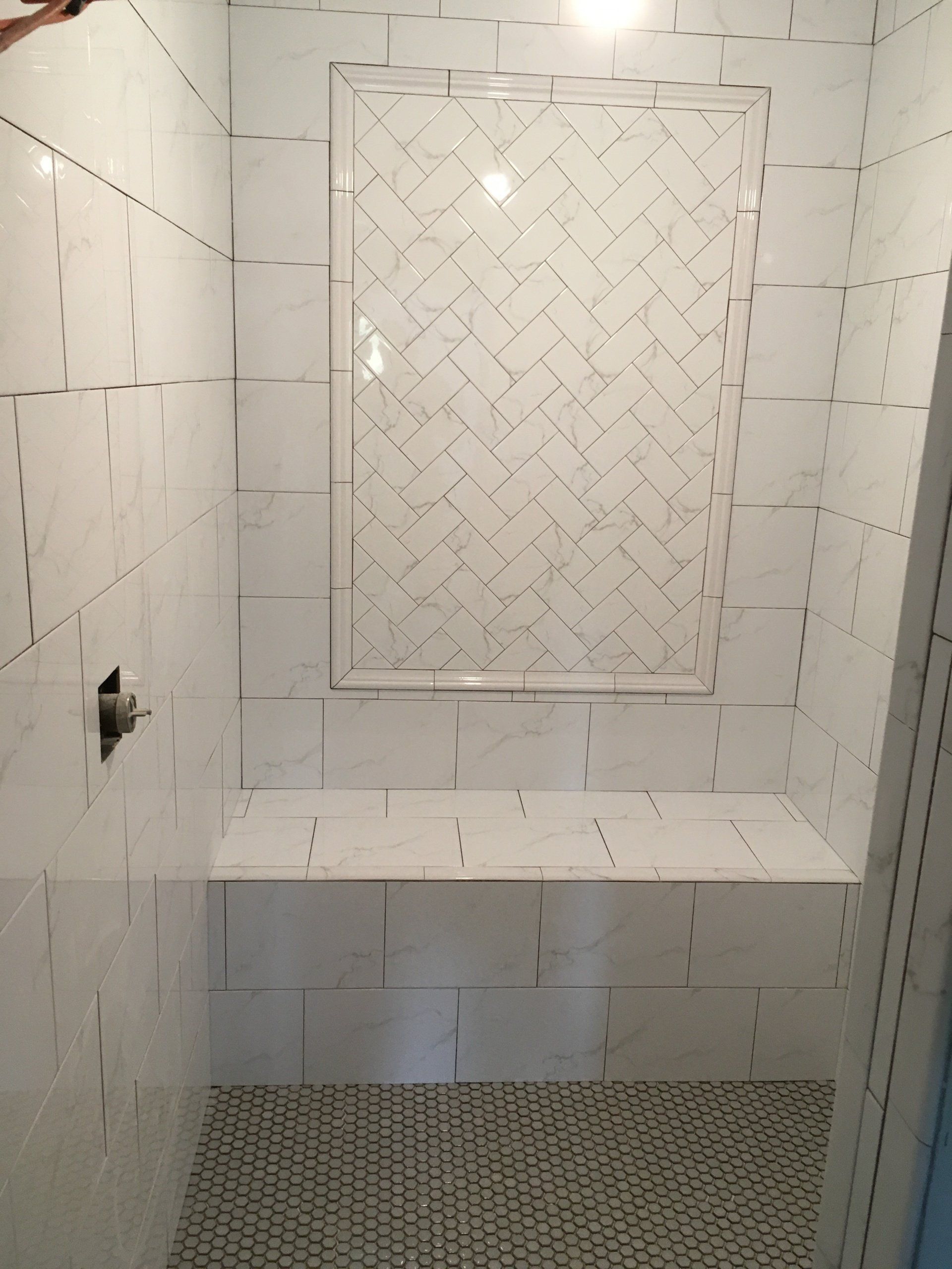 A renovated bathroom with white tiles and a bench