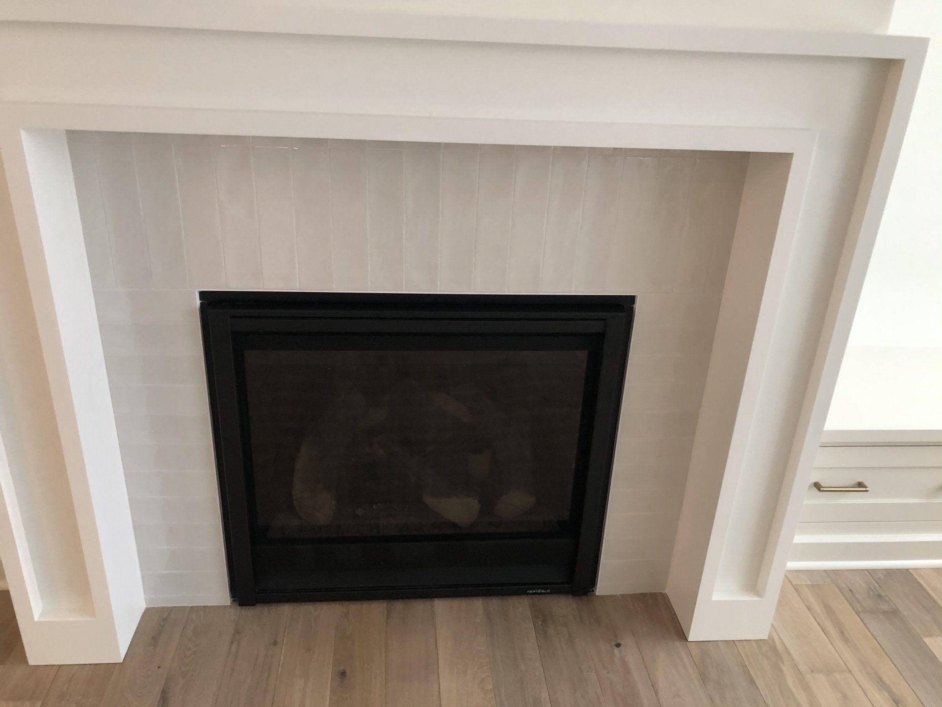 A fireplace with a black screen and a white mantle in a living room.