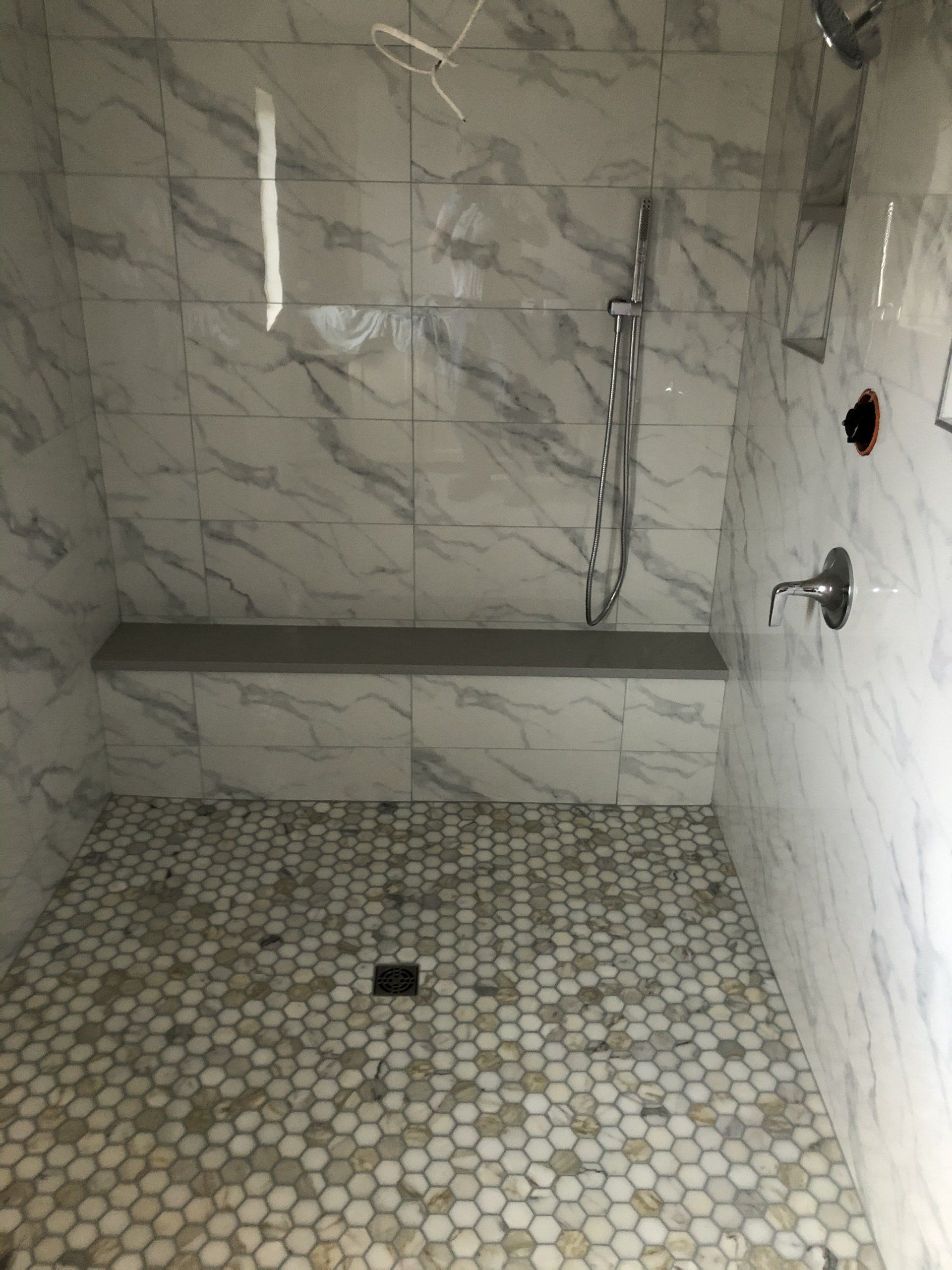 There is a shower with a bench for elderly and a shower head.