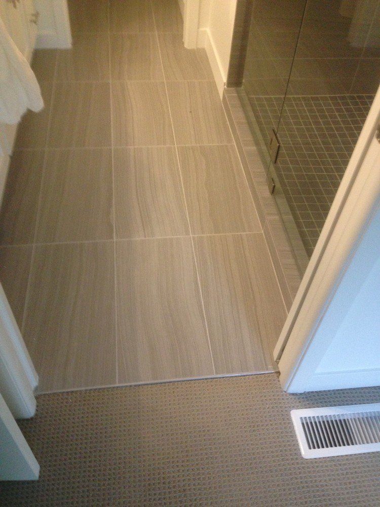 A bathroom with a tiled floor and a walk in shower.