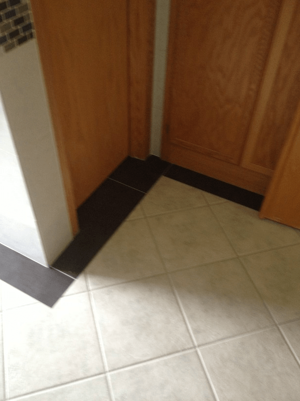 Kitchen and bath remodeling | A corner of a kitchen with a tiled floor and wooden cabinets.