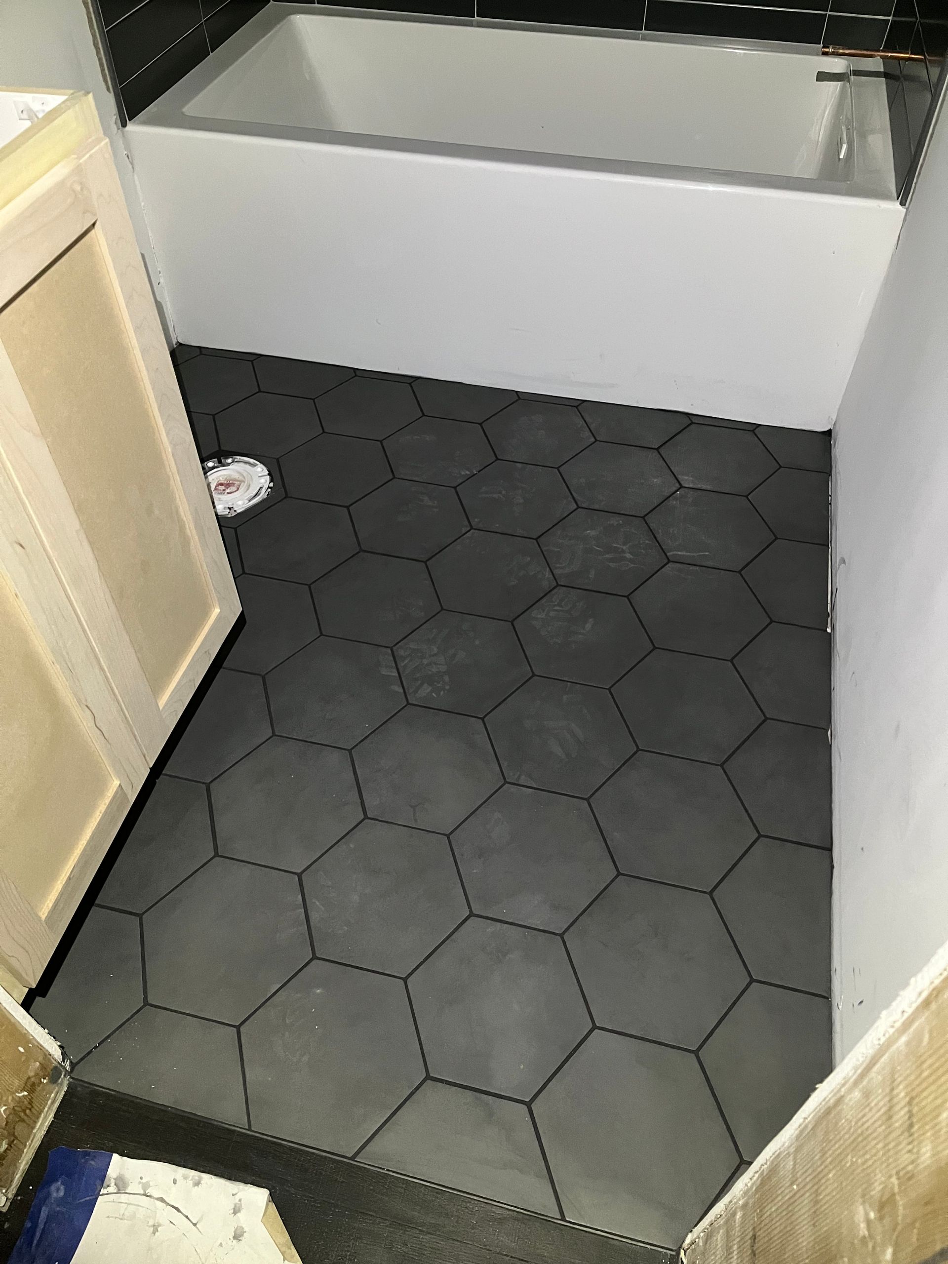 A bathroom with a hexagonal tile floor and a bathtub.