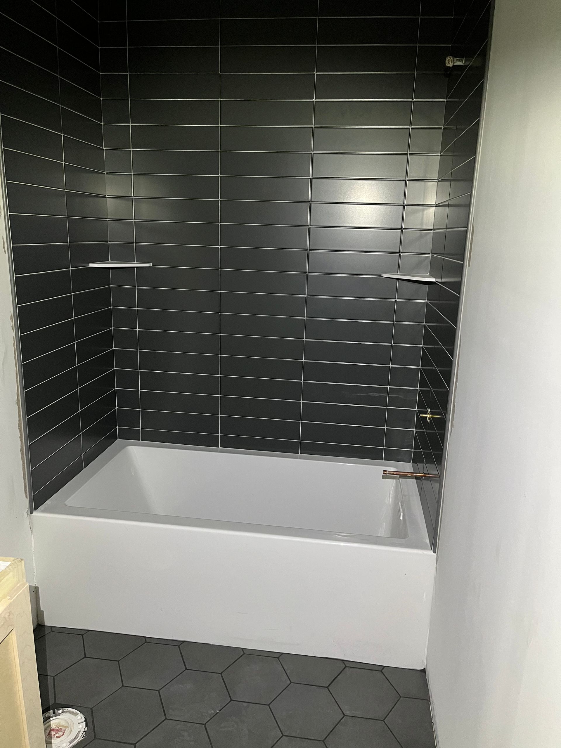 A bathroom with black and white tiles and a bathtub.